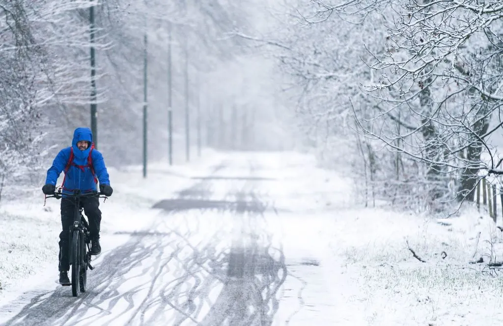Man cycles along snow-covered cycle path.