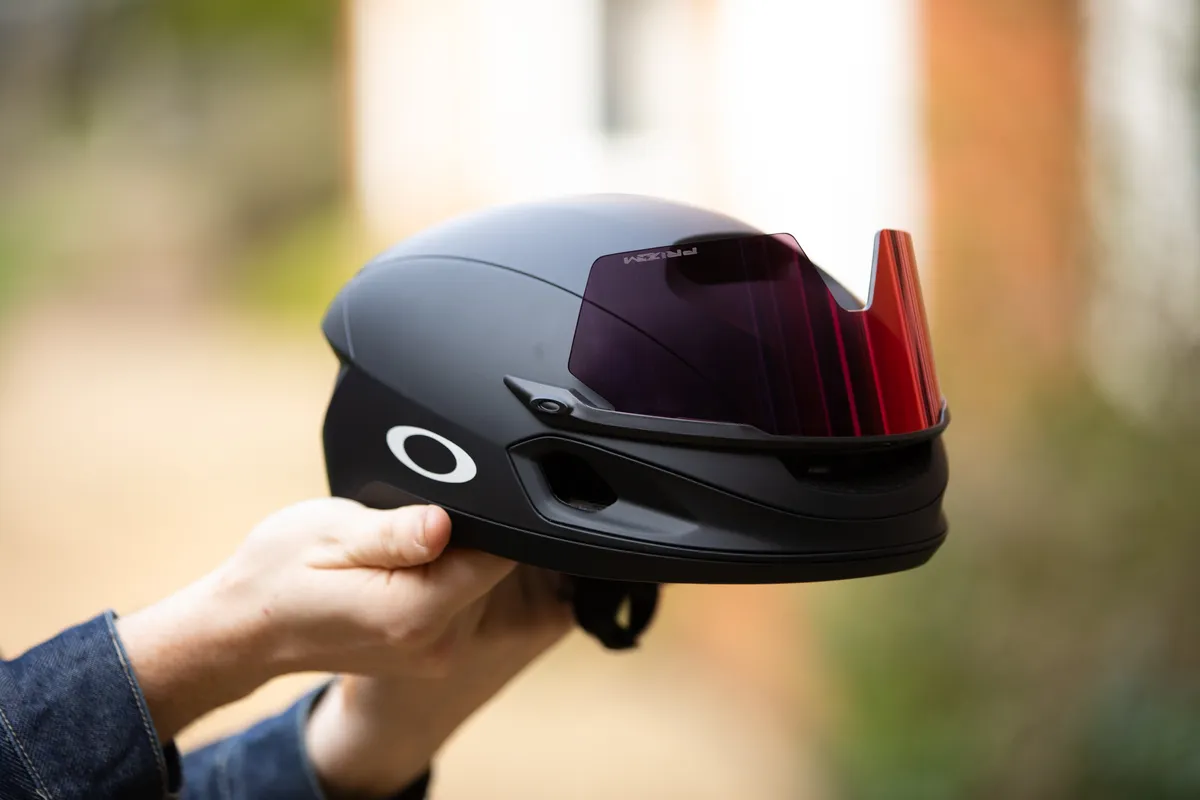 Oakley ARO 7 aero road bike helmet held in hands with visor on top.