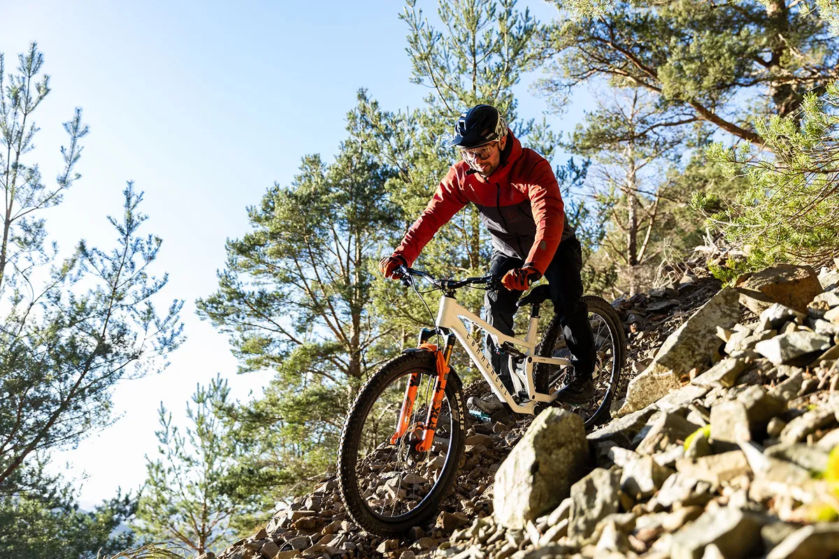Male rider in orange and black top riding the Commencal T.E.M.P.O. LTD full suspension trail mountain bike