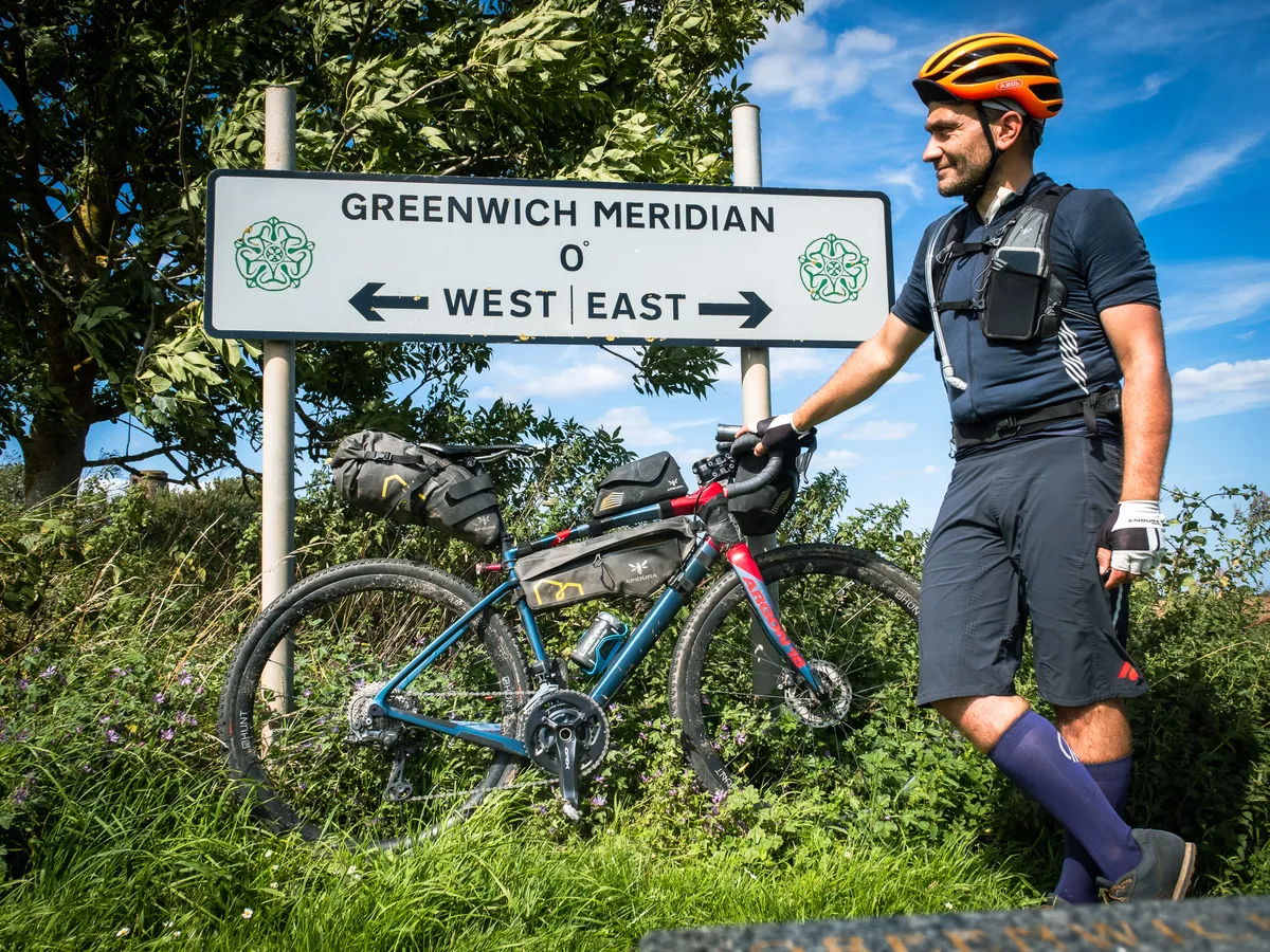 Markus Stitz standing in front of Greenwich Meridian sign