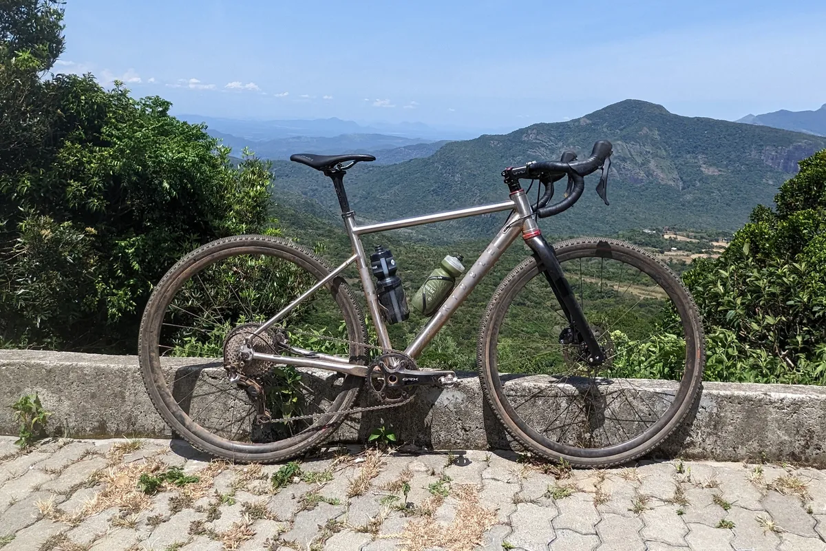 Katherine Moore's Ribble CGR Ti gravel bike leaning against wall with Sri Lankan mountains in background.