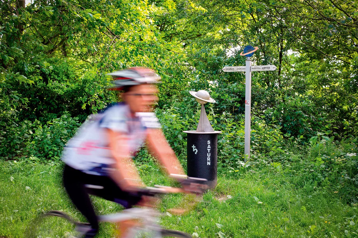 A cyclist passes a model of the planet Saturn on the York to Selby solar cycle path.