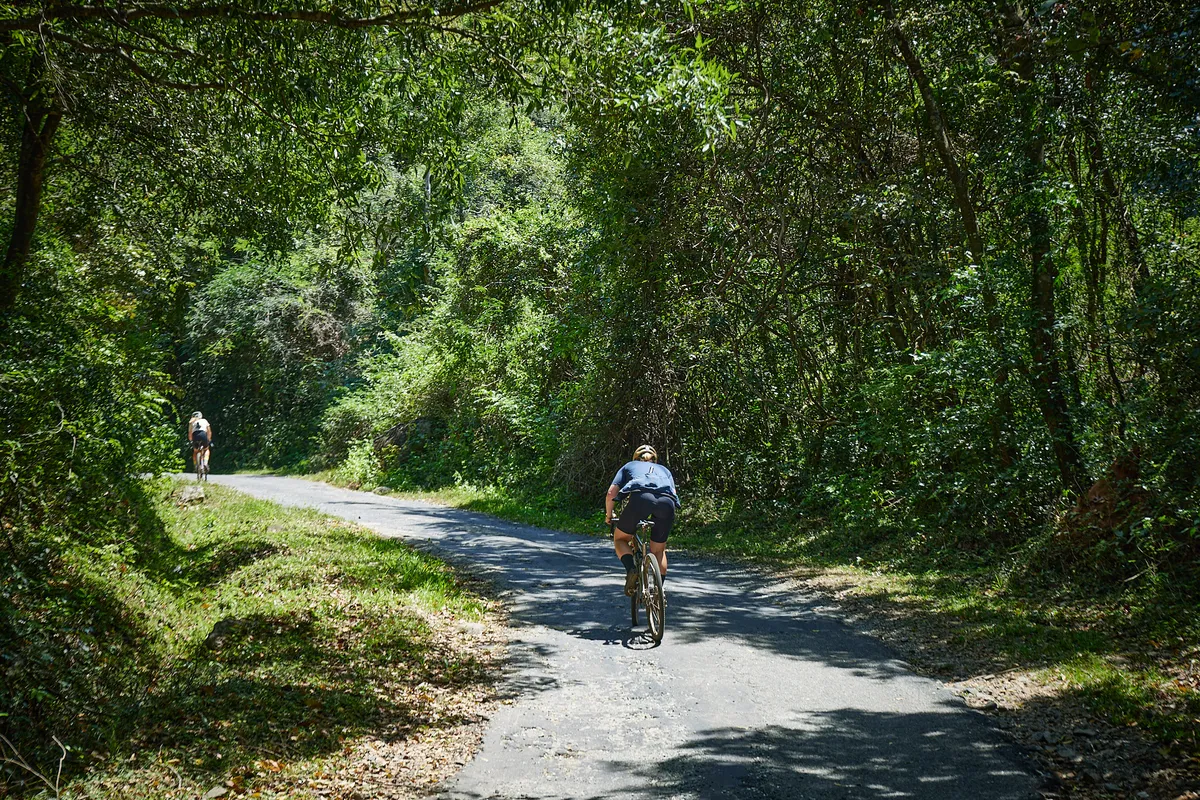 Katherine Moore cycling up road surrounded by green foliage in Sri Lanka.