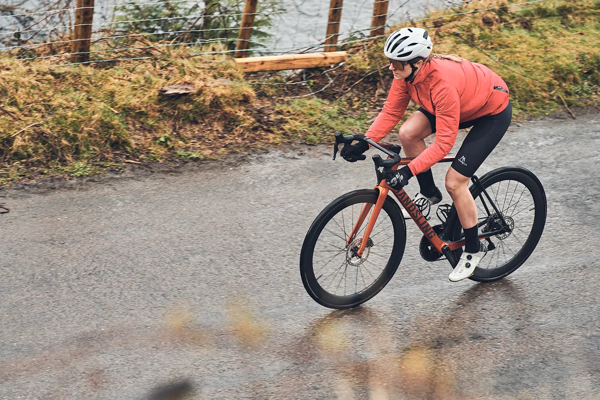 Cyclist in salmon coloured top riding the Handsling A1R0evo road bike