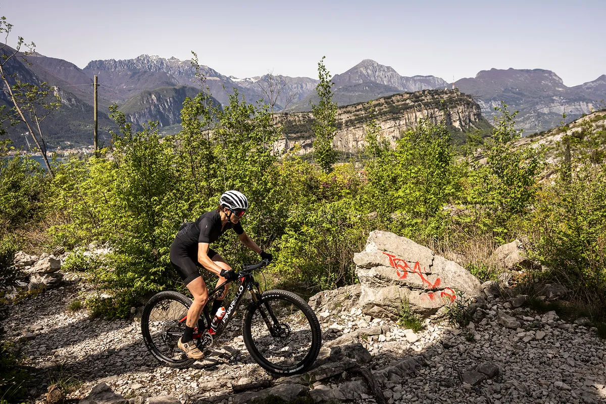 Female rider in black riding the Pinarello Dogma XC full suspension mountain bike up hill