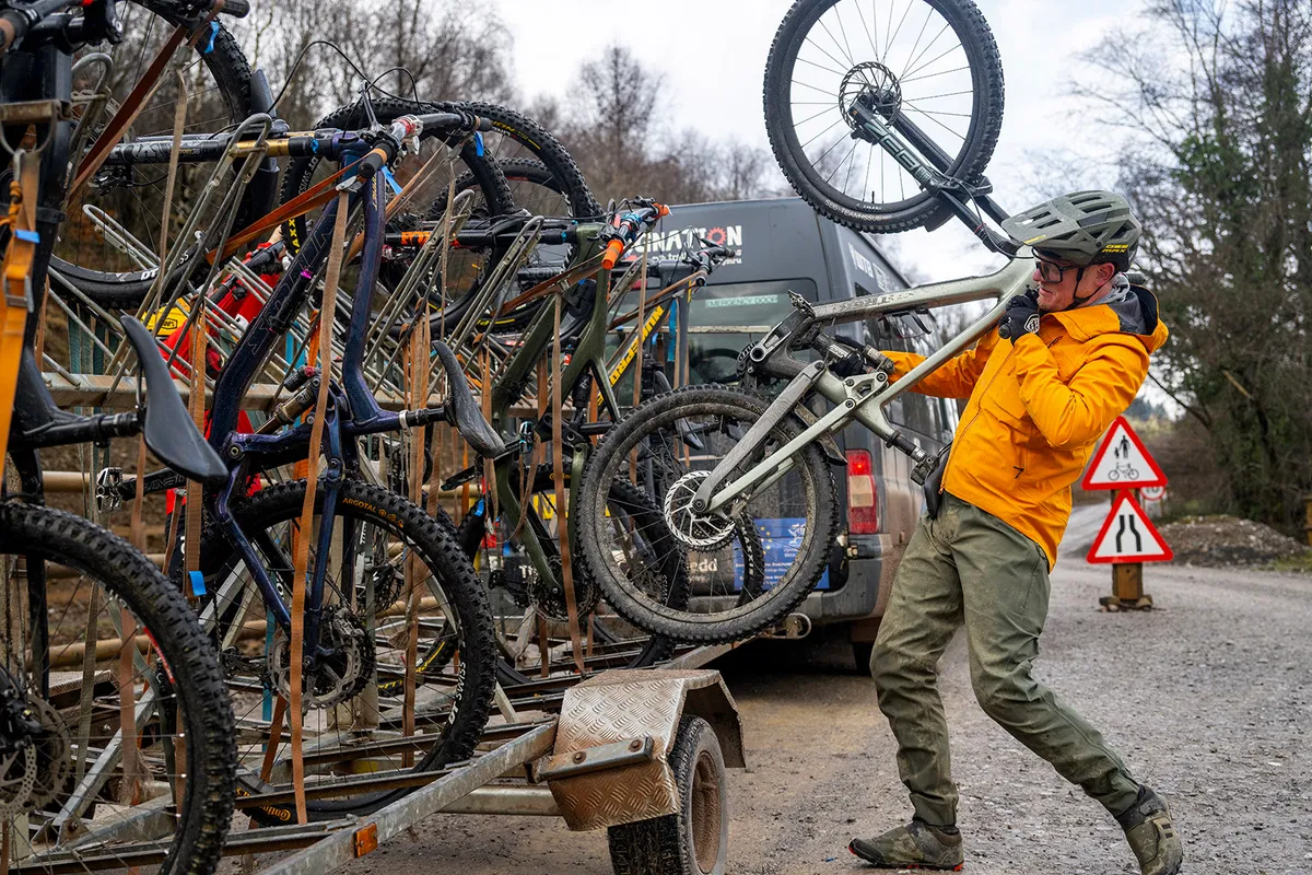 Male mountain biker in yellow top lifting bike onto trailer