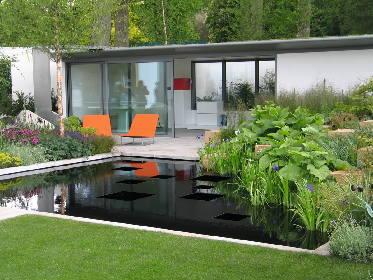 A modern garden office with glass panel doors opening onto a patio and garden pool