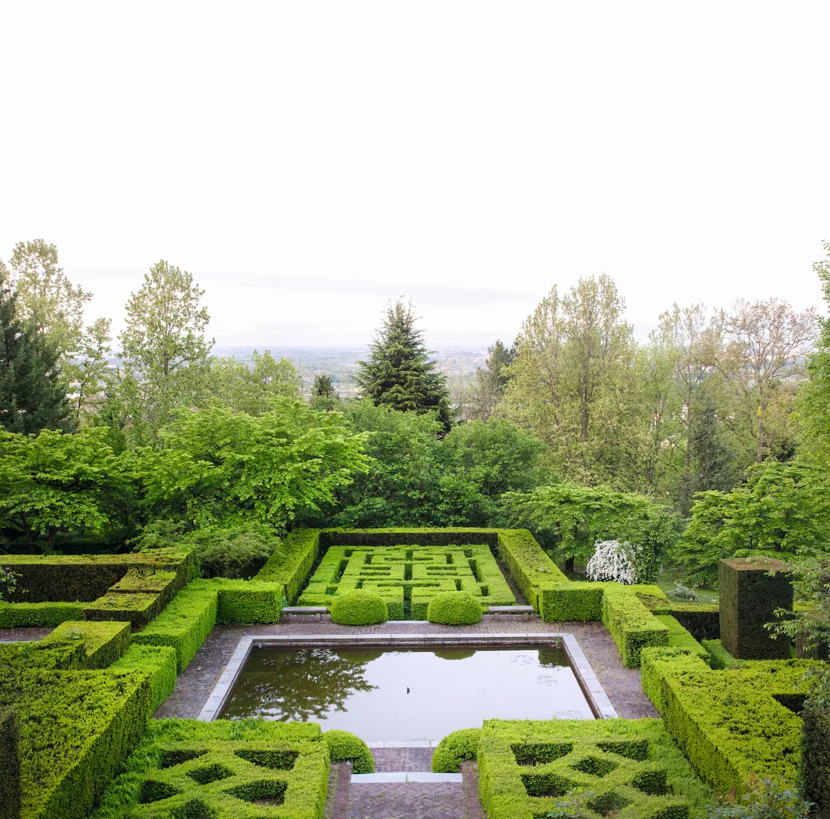 Formal knot garden with relaxed woodland garden on hillside below