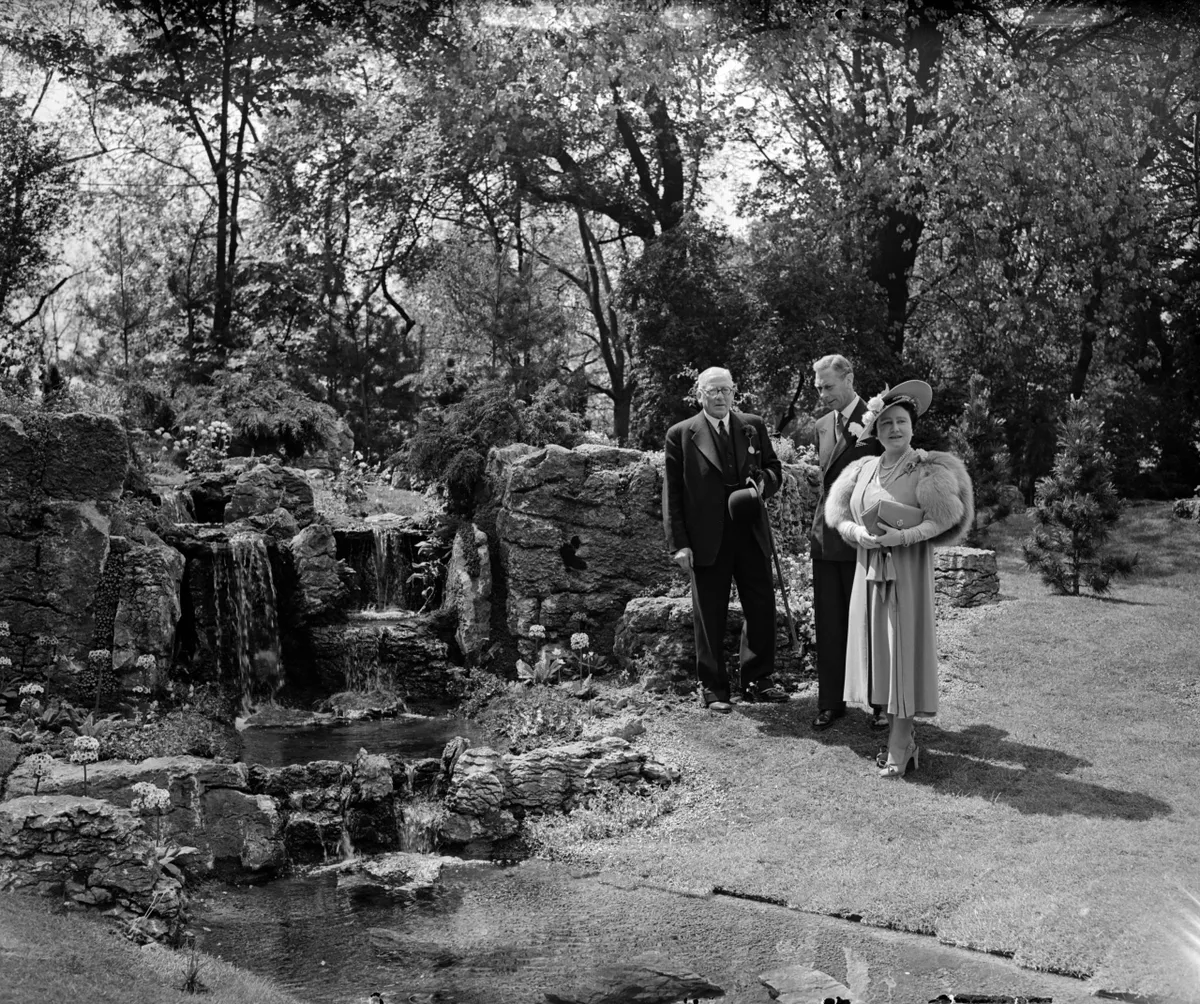 1950: King George VI and Queen Elizabeth talking to the architect of a miniature waterfall built in one of the display gardens at the Chelsea Flower Show