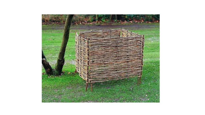 A woven wooden compost bin on grass.