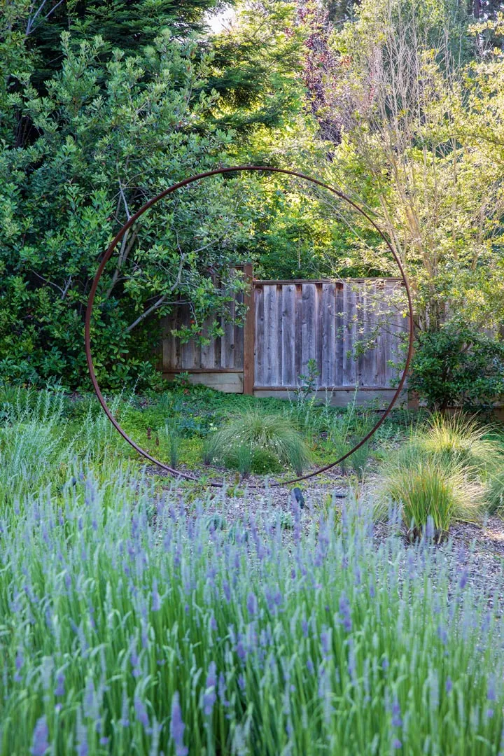 A sculptural metal ring creates a moon-gate effect at the border of the property