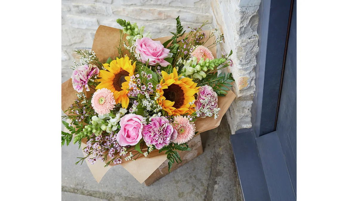A bouquet of flowers in a box on a doorstep.
