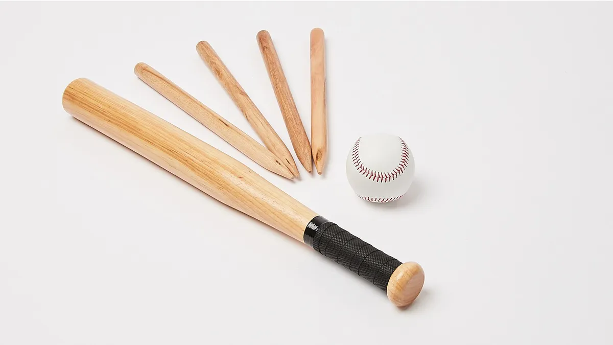 A wooden bat, four markers and a rounders ball on a neutral background.