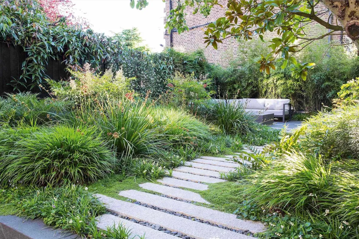 The layered planting in the large bed obscures the seating area from view. A path, softened by mats of Ophiopogon planiscapus, Soleirolia soleirolii and Viola hederacea, slows down the journey to the end of the garden