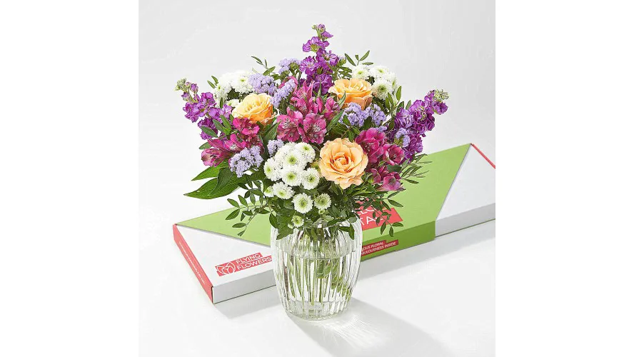 A vase of flowers in front of a colourful box.