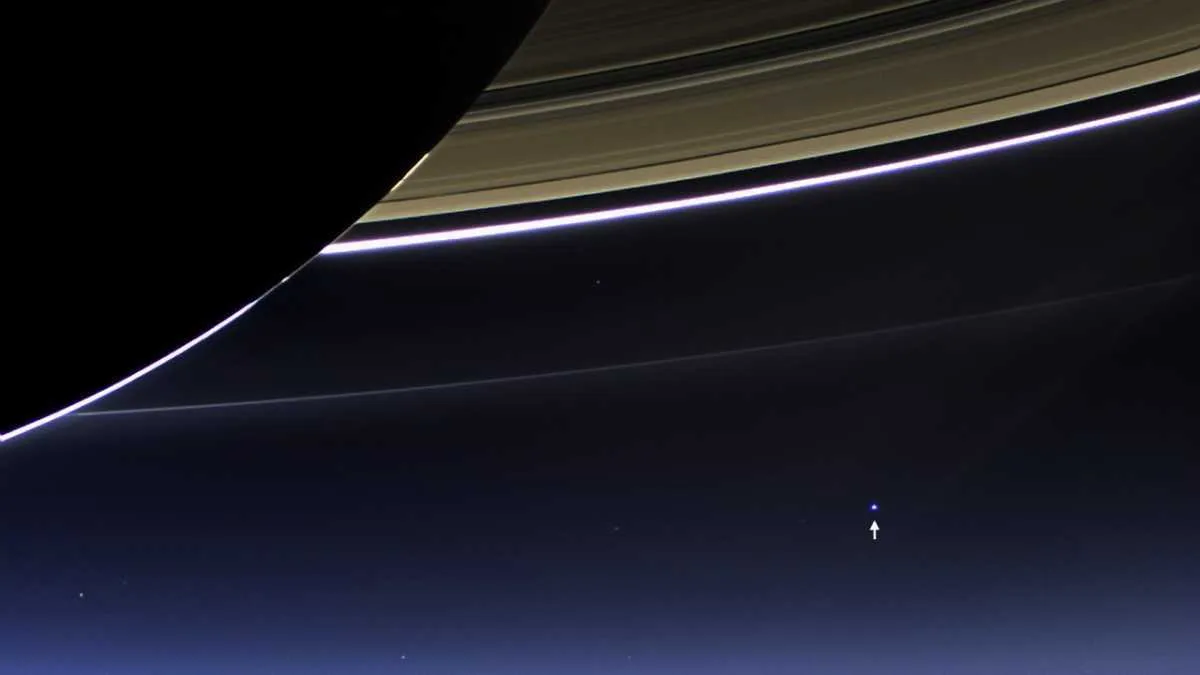 Earth (indicated by arrow) seen behind Saturn © NASA