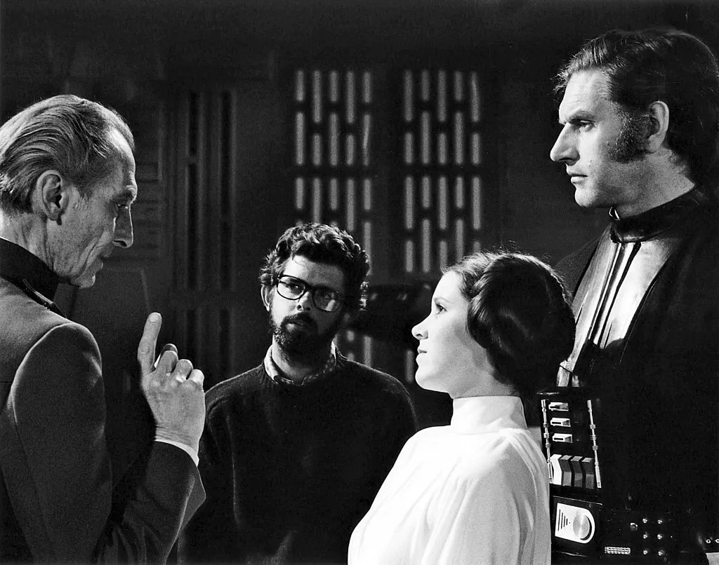British actors Peter Cushing, David Prowse and American Actress Carrie Fisher with director, screenwriter and producer George Lucas on the set of his movie Star Wars: Episode IV - A New Hope © Sunset Boulevard/Corbis via Getty Images