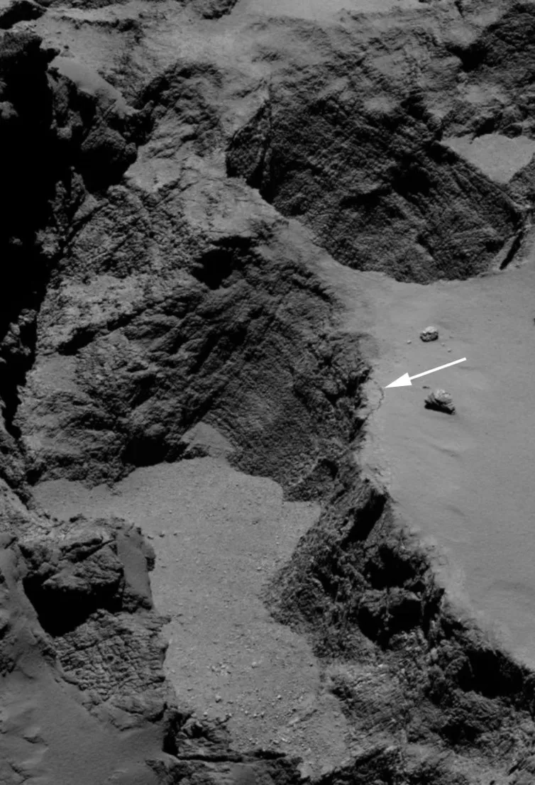 Image of the Aswan cliff. The white arrow shows the 70m long, 1m wide fracture at the edge of the cliff © ESA/Rosetta/MPS for OSIRIS Team MPS/UPD/LAM/IAA/SSO/INTA/UPM/DASP/IDA