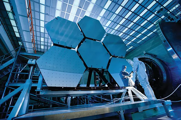 Engineers work on the mirror of the James Webb Space Telescope (JWST)