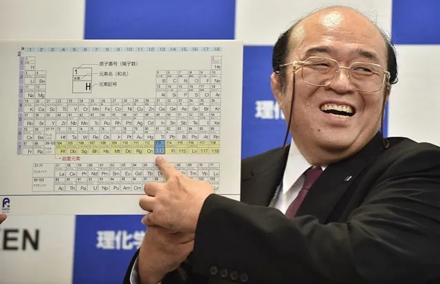 Kosuke Morita smiles as he points to a board displaying the new atomic element 113 during a press conference © Kazuhiro Nogi/AFP/Getty Images
