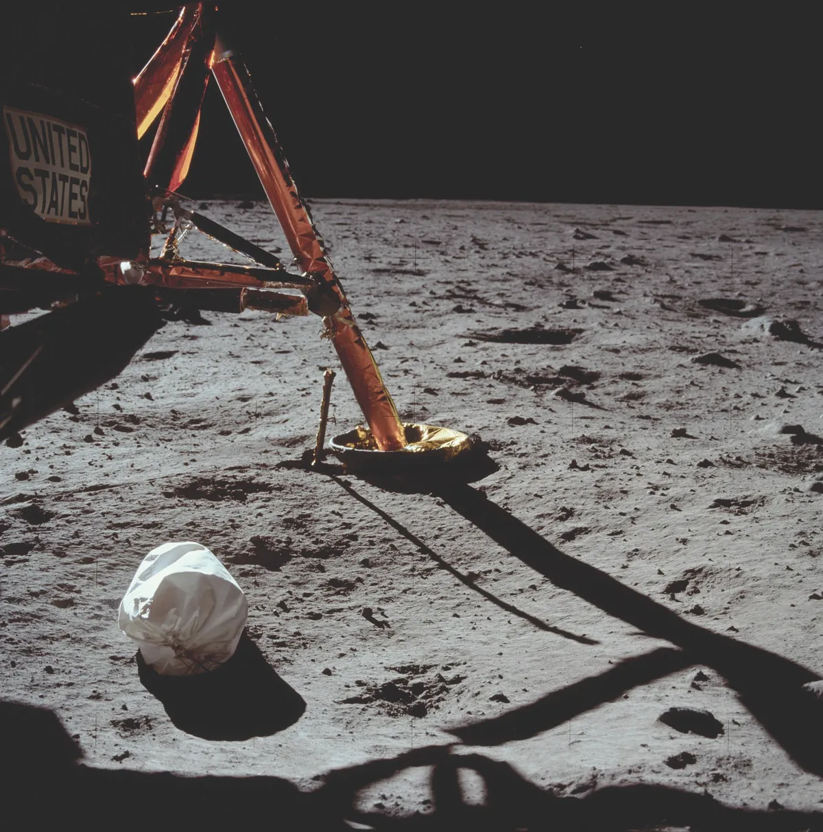 Armstrong’s first photograph on the lunar surface, taken 23 minutes into the moonwalk, shows Eagle’s footpad and strut support, plus a white jettison bag full of rubbish from the lunar module. The bag was left on the surface to free up space in the cramped cabin. © NASA/JPL