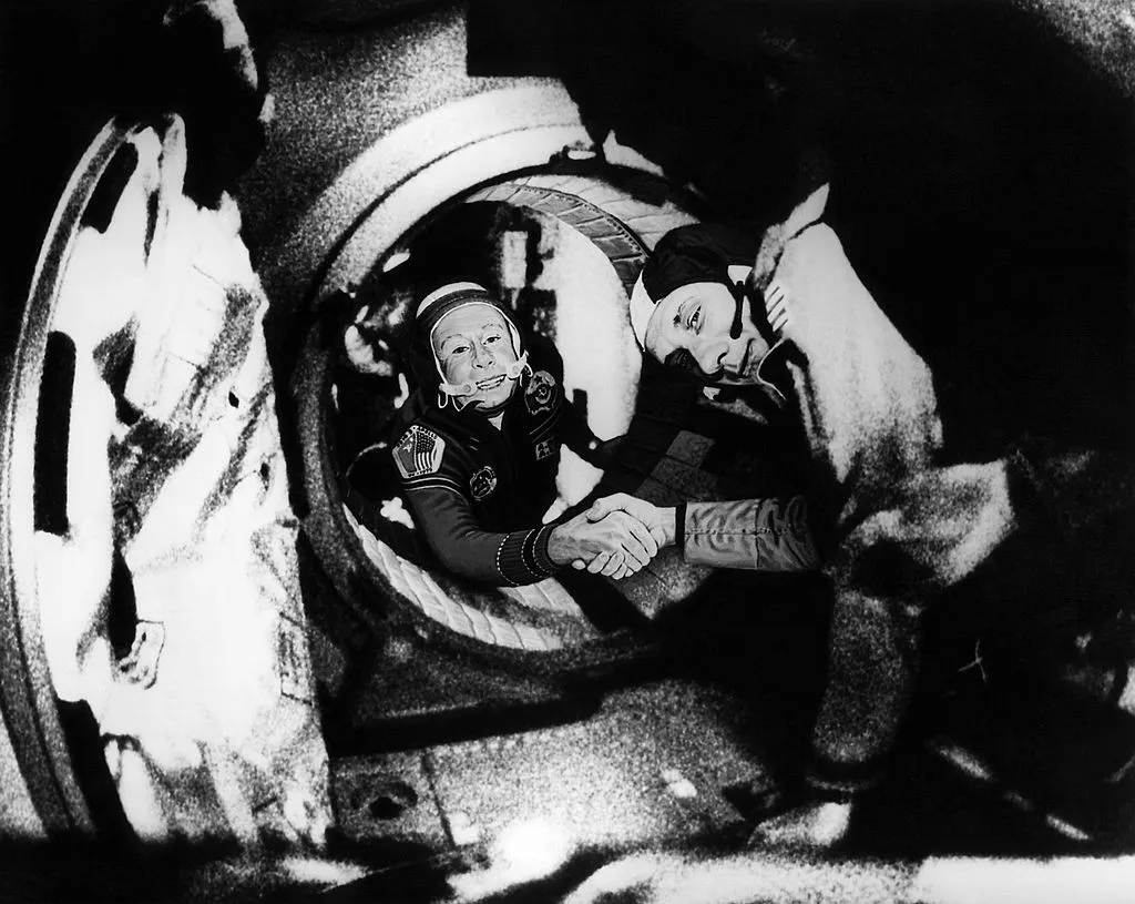 Commander of the Soviet crew of Soyuz, Alexei Leonov (L) and commander of the American crew of Apollo, Thomas Stafford (R), shake hands 17 July 1975 in the space, somewhere over Western Germany, after the Apollo-Soyuz docking manoeuvres © AFP/AFP/Getty Images