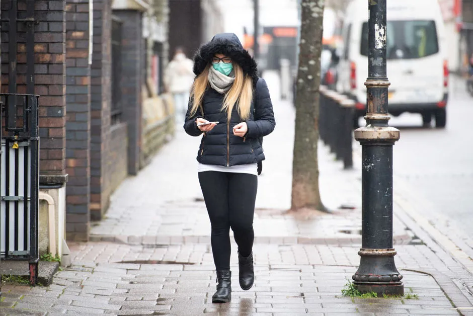 A woman walks along the street wearing a surgical mask in Cardiff on 17 March © Getty Images