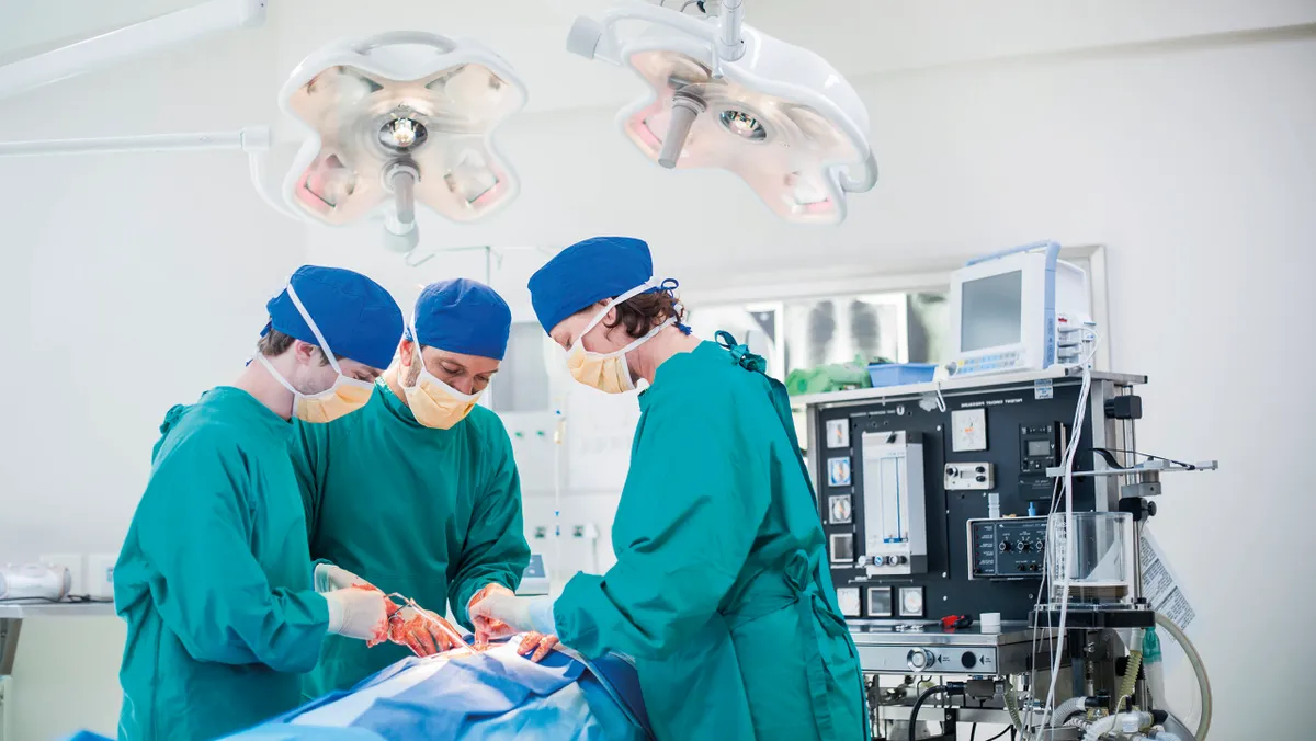 Three surgeons performing a surgery on a patient in operating room