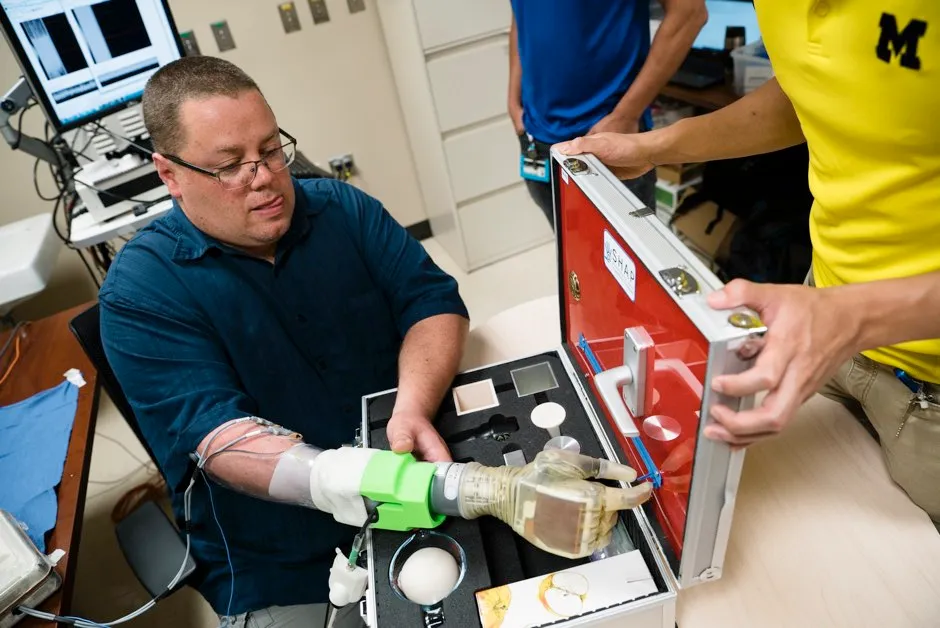 Study participant Joe Hamilton uses his mind to control his prosthetic hand to pinch a small zipper on a hand development testing platform © Evan Dougherty/University of Michigan Engineering
