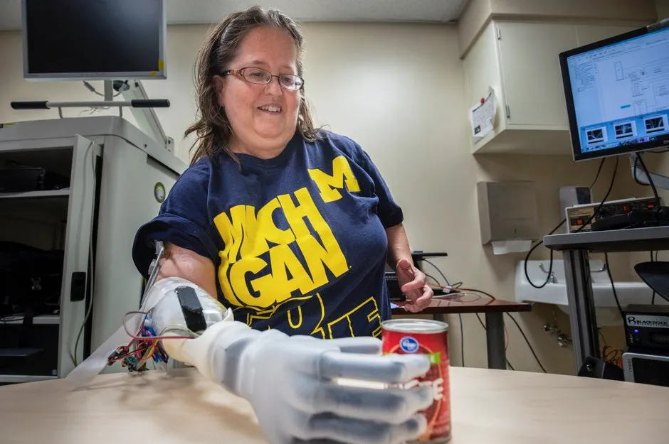 Study participant Karen Sussex uses her mind to control her prosthetic hand to pick up a can of tomato paste © Robert Coelius/University of Michigan Engineering