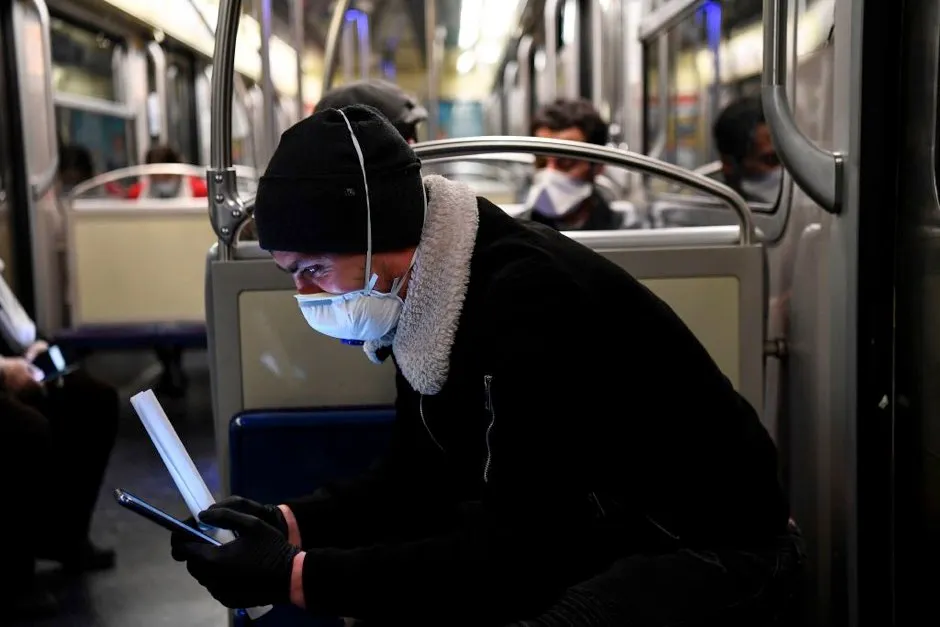 A commuter wearing a protective facemask studies a smartphone as he sits with others in the carriage of a metro in Paris © Alain Jocard/AFP via Getty Images