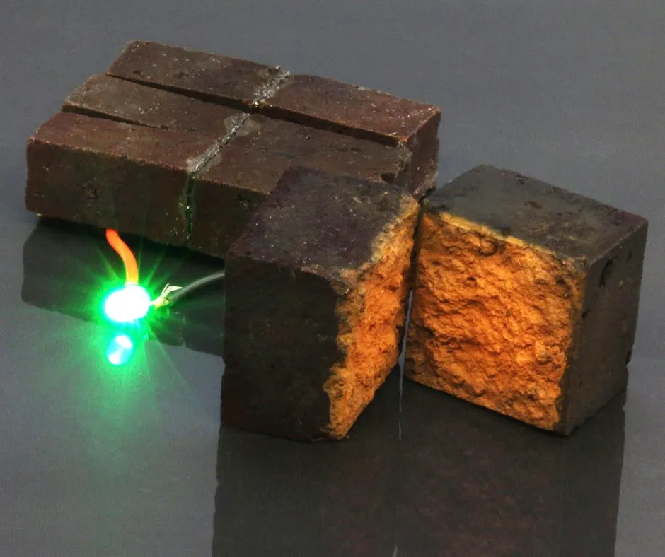 Red brick device developed by chemists at Washington University in St. Louis lights up a green light-emitting diode (D'Arcy laboratory: Washington University in St. Louis)