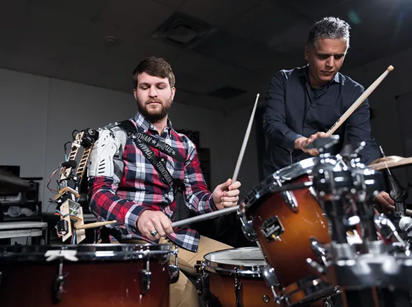 Gil Weinberg with Tyler White playing drums with a robotic arm