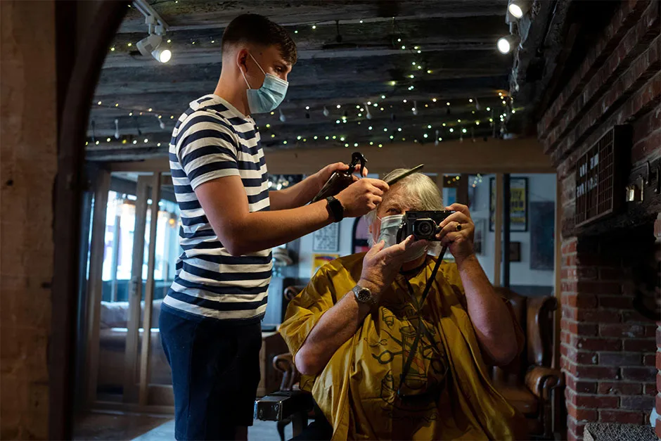A person in a face mask receiving a hair cut © Alamy