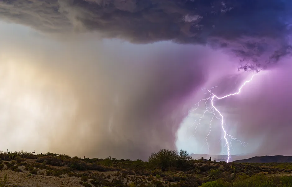 Lightning strikes beside a powerful microburst from a monsoon thunderstorm near Florence, Arizona.