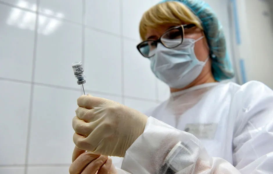 A healthcare worker filling a syringe from a small bottle © Getty Images