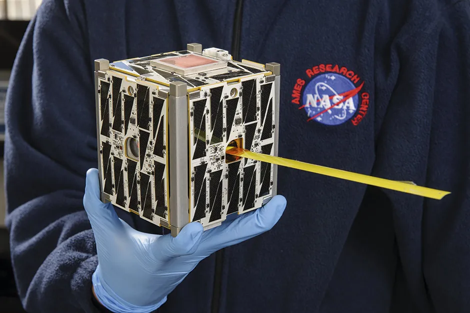 A person holding a CubeSat in one hand © NASA/JPL