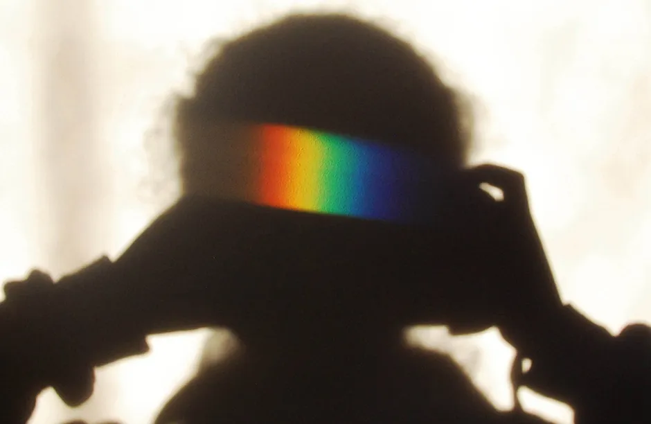 Sunlight casts a spectrum on a wall having passed through a prism. The photographer cast her own shadow on the wall to let the spectrum shine more clearly.