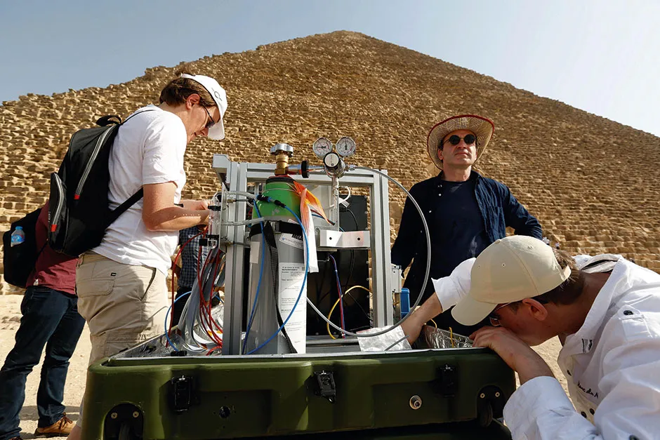 Some members of the ScanPyramids team set up one of the project’s muon detectors in front of the north face of the Pyramid of Khufu © Alamy
