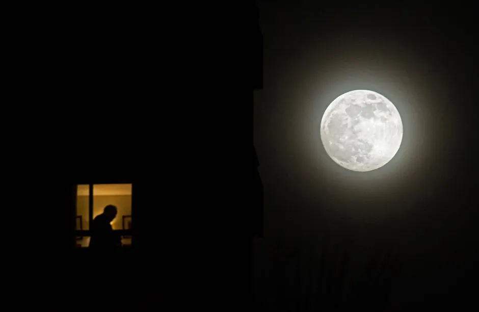 MALLA, SPAIN - 2021/05/26: The second super full moon of the year, known as 'flower moon', rises over the sky as a man is seen silhouetted inside a building. The super moon is an astronomical event that produces a visual effect in the moon with an appearance bigger and shiny than normal. (Photo by Jesus Merida/SOPA Images/LightRocket via Getty Images)