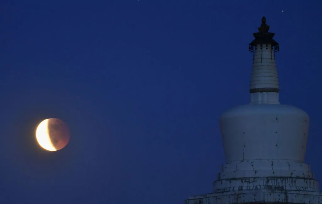 The lunar eclipse is observed over the White Dagoba at Beihai park on May 26, 2021 in Beijing, China. (Photo by VCG/VCG via Getty Images)