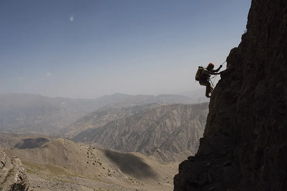 A climber on a rope descending a rock face © Robbie Shone