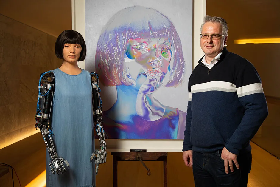 Aidan Meller with Ai-Da and one of her self-portraits © David Parry/PA