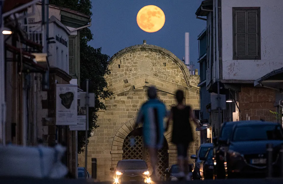 People walk beneath the rising Strawberry super moon towards the Venetian-built Famagusta gate in the old walled city of Cyprus' capital Nicosia on June 24, 2021. - Famagusta gate, one of the three main gates of the old city of Nicosia, was built in 1567 during the period of Venetian rule of the island of Cyprus. It was subsequently restored in 1821 during the reign of Ottoman Sultan Mahmud II, with the Sultan's seal (tugra) displayed atop its gatehouse. (Photo by Amir MAKAR / AFP) (Photo by AMIR MAKAR/AFP via Getty Images)