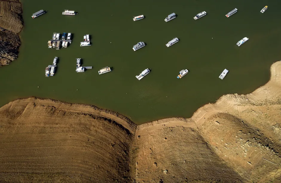 OROVILLE, CA - JUNE 08: In an aerial view, houseboats whose owners chose to leave them in the lake, float near the lake's shore at the Lime Saddle Marina for Lake Oroville near Paradise, Calif., on Tuesday, June 8, 2021. Drought has caused the water level to drop in Lake Oroville several hundred feet, leaving houseboat owners to make a choice to leave their craft in the water or to remove them since boat ramps will not reach the low level of the water as it drops lower and lower. (Carlos Avila Gonzalez / The San Francisco Chronicle via Getty Images)