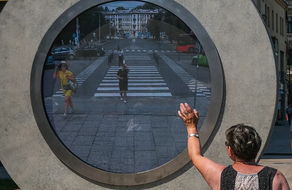 LUBLIN, POLAND - JULY 07 : A woman waves to a real-time video portal connecting Lublin and Vilnius at the Lithuanian square on July 07, 2021 in Lublin, Poland. The virtual bridge allows people from the Lithuanian capital to interact with passersby at the âother endâ of the portal, in Lublin located more than 550 km away.In the future, there are plans to also build portals connecting Vilnius to Reykjavik and London. (Photo by Omar Marques/Anadolu Agency via Getty Images)