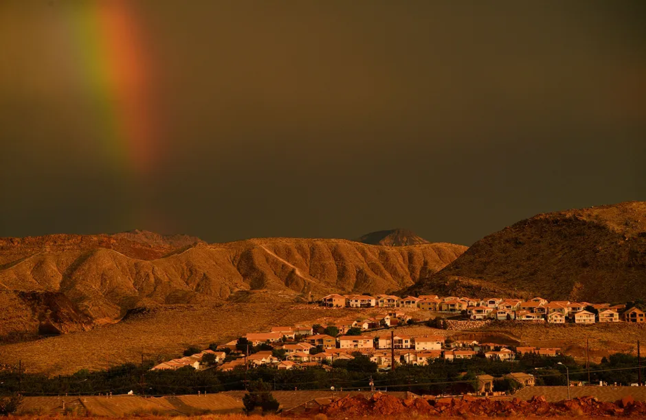 TOPSHOT - A rainbow shines behind homes on a hillside during the western drought on July 20, 2021 in St. George, Utah. - An approximately 140-mile water pipeline is proposed to bring additional water from the Colorado River and Lake Powell in Arizona to communities in southern Utah. (Photo by Patrick T. FALLON / AFP) (Photo by PATRICK T. FALLON/AFP via Getty Images)