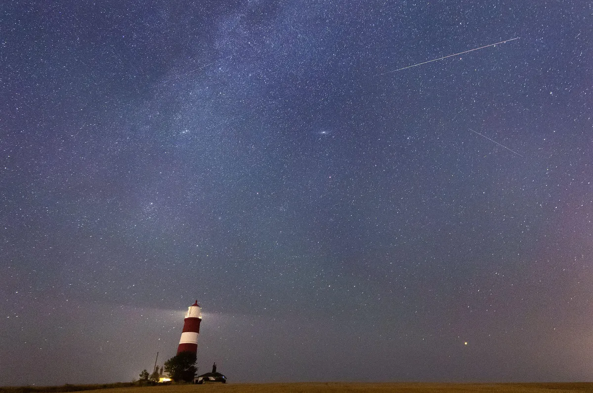 A meteor during the Perseid meteor shower seen over Happisburgh lighthouse, Norfolk. Sky gazers are set to be treated to a light display next week as Earth passes through debris left behind by a comet. Issue date: Friday August 6, 2021.