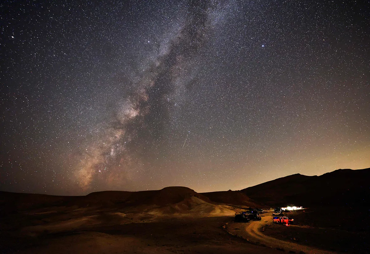 The Milky Way galaxy is pictured as a Perseid meteor streaks across the sky above the Negev desert near the Israeli city of Mitzpe Ramon, on August 12, 2021, during a yearly meteor shower, which occurs when the earth passes through the cloud of debris left by the comet Swift-Tuttle. (Photo by Menahem KAHANA / AFP) (Photo by MENAHEM KAHANA/AFP via Getty Images)