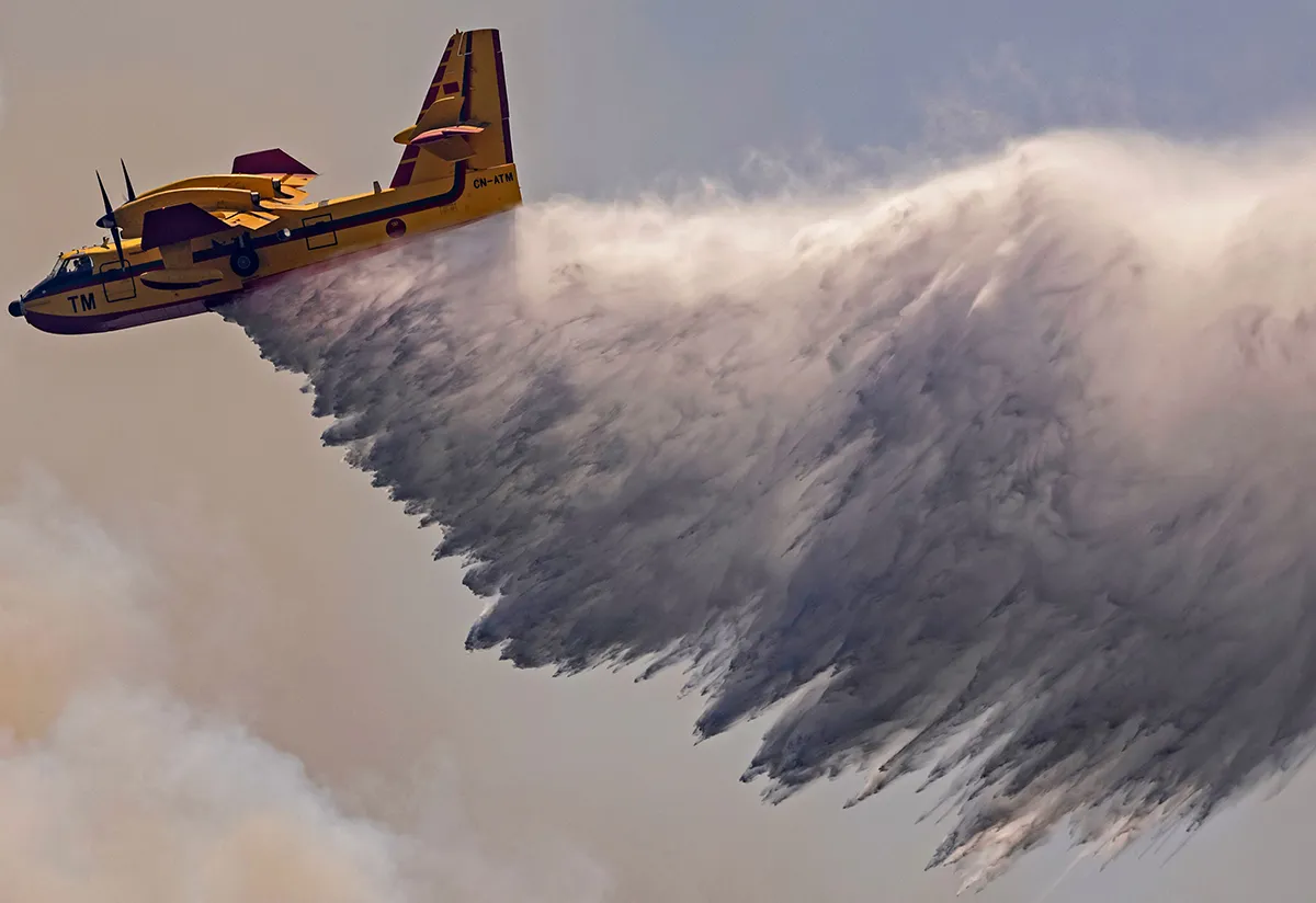 A Royal Moroccan Air Force Canadair plane douses a wildfire in the region of Chefchaouen of northern Morocco on August 17, 2021. - Firefighters in northern Morocco are battling to put out two forest blazes, a forestries official said as the North African kingdom swelters in a heatwave. Firefighting planes were being used to tackle the conflagrations which had already destroyed some 200 hectares (500 acres) of forest. (Photo by FADEL SENNA / AFP) (Photo by FADEL SENNA/AFP via Getty Images)
